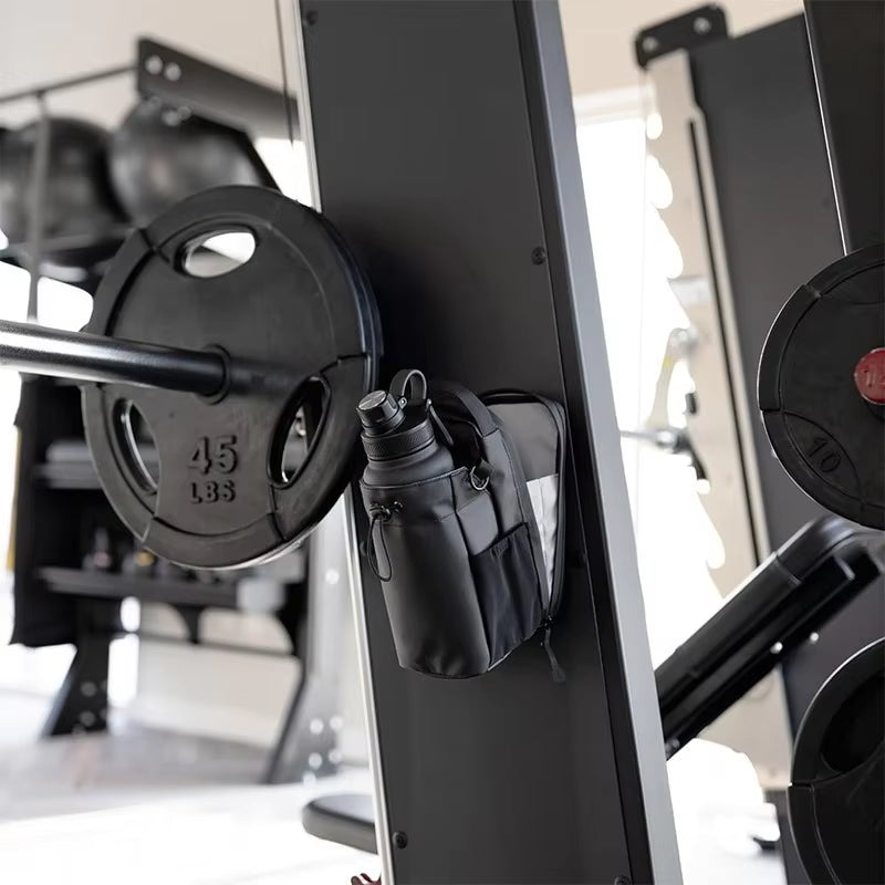 Black weight plate on a barbell with a small black bag attached, in a gym setting.